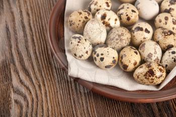 Quail eggs in a clay plate on a wooden background