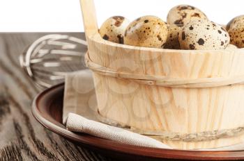 Quail eggs in a wooden bucket on a wooden table