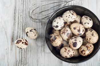 Quail eggs in a black dish on a wooden background. Top view.