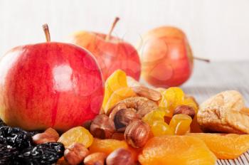 Ripe red apples on a wooden background. Juicy apples, nuts and dried fruits on a table.