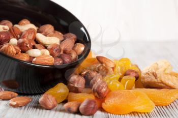 Dried fruits and nuts on a wooden background. Candied fruits, lemon, apricot, fig and nuts in black plate. 