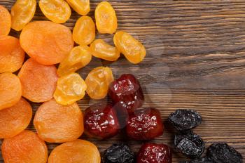 Dried fruits on a wooden background. Apricots, dates, lemons and plums.