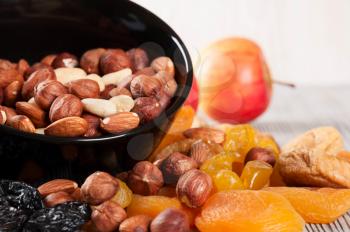 Dried fruits, lemon, apricot, fig and nuts in black plate on a wooden background. 