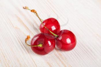 Three red sweet cherries on awooden background