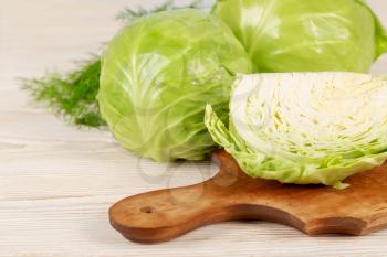 Fresh white cabbage and green dill for salad on a wooden cutting board. Vegetarian and healthy diet food concept. 