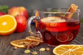 Mulled wine with spices and fruit on a brown wooden table. Traditional Christmas hot drink with red wine, apples, oranges and cinnamon