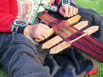 Close up of Peruvian lady in authentic dress spinning yarn by hand. (Peru)