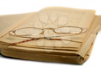 old open shabby book and reading glasses lying on it