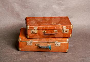 Old long out of fashion redhead closed suitcases on gray background