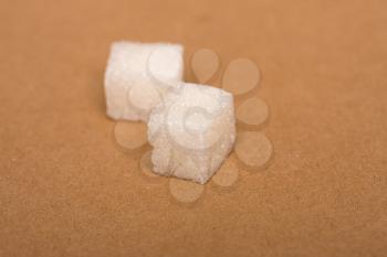 two cubes of white sugar refined on a beige background of kraft paper