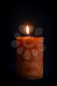 Wax candle with a burning light on a dark background