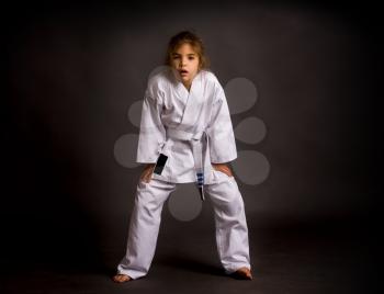 A little tired girl karate in a white belt, but already received three stripes are excited