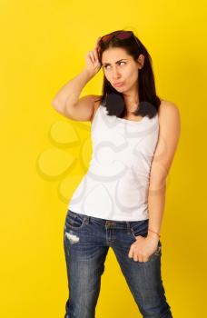 Emotional pretty young girl grimacing in sunglasses on bright yellow background in casual clothes