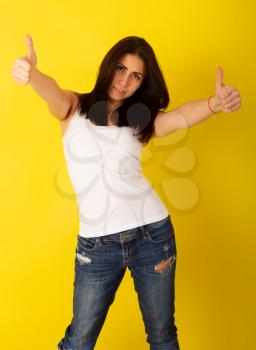 Young cute girl in casual clothes shows a thumbs up in an approving gesture on a bright yellow background