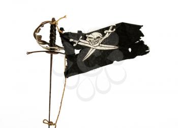 Black pirate flag winding up in the wind tied with a rope to an old sword