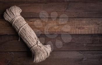 A large skein of coarse natural rope close-up on a wooden background