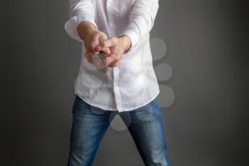 A man in a white shirt and jeans holds in his hands a large steel kitchen knife on a dark background