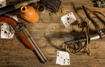 Pirate wooden table with weapons alcohol coins and playing cards