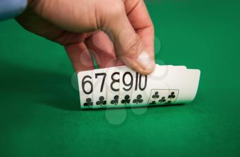 Close-up of an adult man's hand in a casino holding a winning card combination