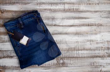 New classic blue jeans with blank labels lie on a rough wooden background as seen from the front pocket 