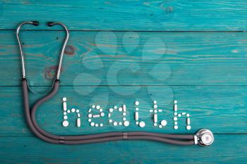 Health concept - pills, stethoscope on the wooden desk