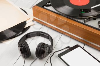 Vintage turntable, smartphone and headphones on the wooden background
