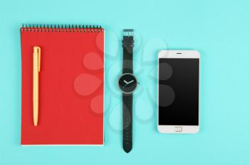Phone, notepad, watch and pen on the blue background