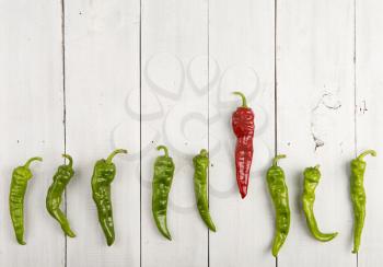 Leadership concept - red hot chili pepper leading the group of green peppers