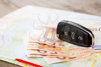 Car rental concept - car key and money on the road map