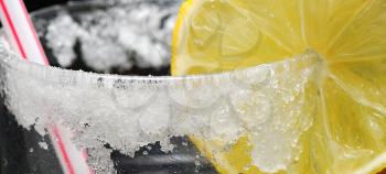 Detail image of coctail with lemon, straw and sugar.