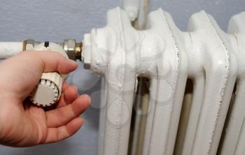Hand on the thermostatic controller on the radiator.