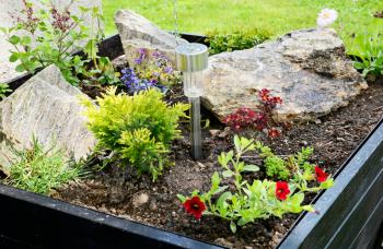 Ornamental flowerpot with flowers, stones and solar lamp.