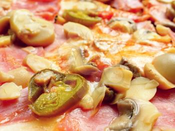 Closeup of a pizza with chili peppers, ham and mushrooms. 