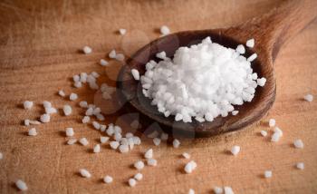 White clear salt crystals on a wooden spoon.