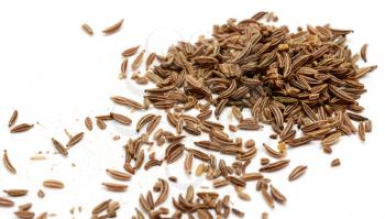 Scattered caraway seeds on white background.
