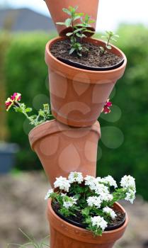 Stacked ornamental flower pots with blooming flowers.