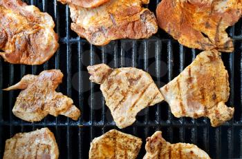 Top view of pork and chicken marinated slices on grill during BBQ grilling.