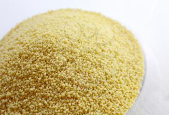 Closeup of raw uncooked cous cous heap in the bowl.
