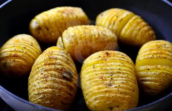 Closeup of sliced baked crispy hasselback potatoes in the pan.