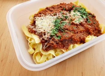 A Closeup of Tagliatelle Bolognese with Parmesan and Parsley in Takeaway Plastic Box.