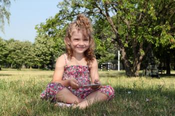 little girl with tablet pc in park
