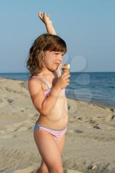 child eat ice cream on beach