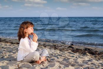 little girl play pan pipe on beach