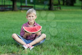 happy boy with watermelon sitting on grass
