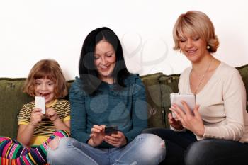 happy mother and daughters playing with smart phones and tablet