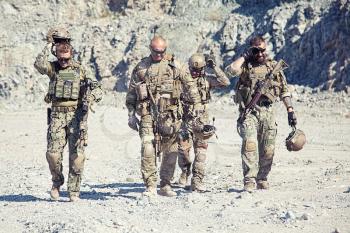 Team squad of special forces in action in the desert among the rocks