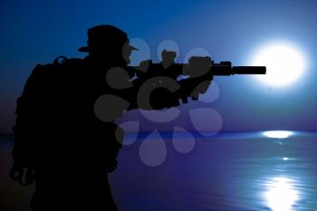 Army soldier with rifle night moon silhouette under cover of darkness. Covert diversionary operation