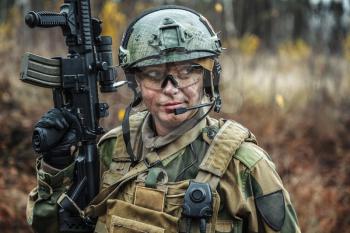 Norwegian Armed Forces Special Command FSK female soldier closeup portrait. Protective eye-wear and assault gun