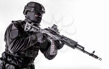 Studio portrait of police special forces member, quick reaction group shooter in black uniforms, helmet, hidden behind mask and glasses face, armed with assault rifle isolated on white, copyspace
