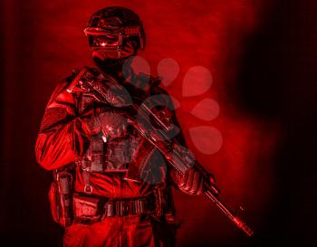 Police assault team member, special forces soldier, private security service, military company serviceman in black ammunition and uniform, armed service rifle, high contrast studio shoot on black